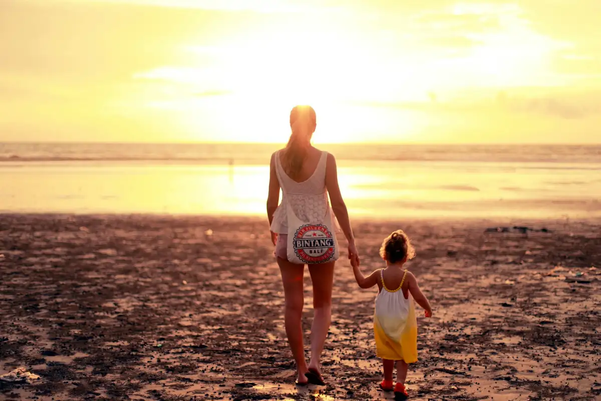 Mother and child walking on a Bali beach at sunset